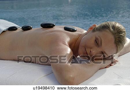 Stock Image - Hot stone massage - woman on the massagebed. Fotosearch