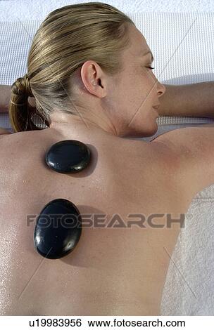 Stock Photograph - Hot stone massage - woman on the massagebed. Fotosearch
