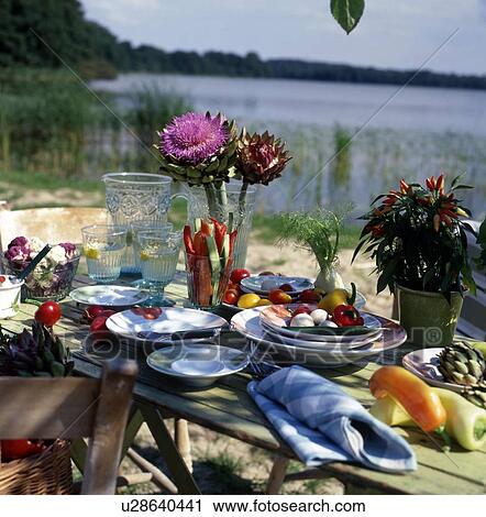 Stock Image - Laid table outdoors with vegetables. Fotosearch