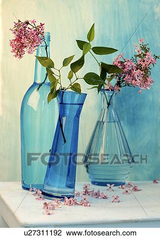 Stock Image - Lilac in blue bottles. Fotosearch