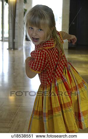 Stock Image - Little girl in a yellow and red checked dress. Fotosearch