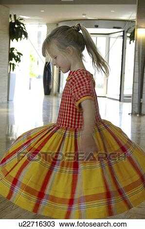 Stock Image - Little girl in a yellow and red checked dress. Fotosearch