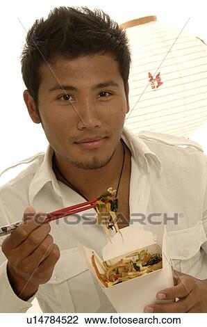 Stock Image - Man eating asian dish with chopsticks. Fotosearch