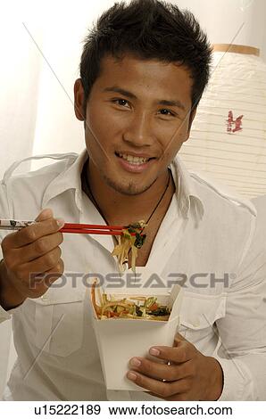 Stock Photo - Man eating asian dish with chopsticks. Fotosearch