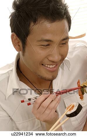 Man eating sushi with chopsticks View Large Photo Image Picture - Man eating sushi with chopsticks. Fotosearch