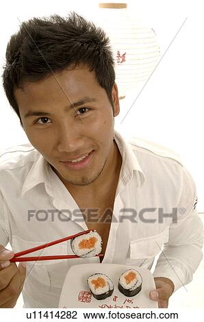 Stock Image - Man eating sushi with chopsticks. Fotosearch