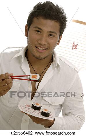 Stock Image - Man eating sushi with chopsticks. Fotosearch