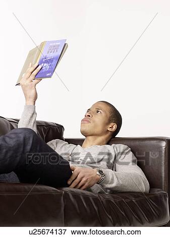 Man lying on couch reading book View Large Photo Image Stock Photo - Man lying on couch reading book. Fotosearch