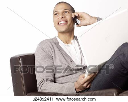 Man using cell phone and laptop View Large Photo Image Stock Image - Man using cell phone and laptop. Fotosearch