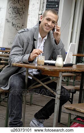 Stock Image - Man with laptop in outdoor café. Fotosearch