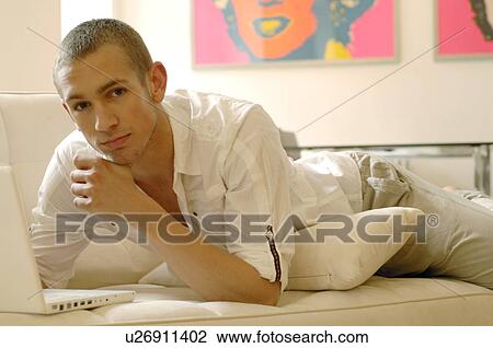 Stock Image - Man with laptop lying on the couch. Fotosearch