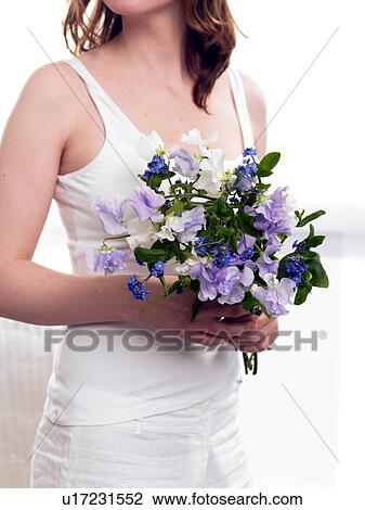 Stock Image - Model holding a bouquet of sweet pea and forget-me-not. Fotosearch