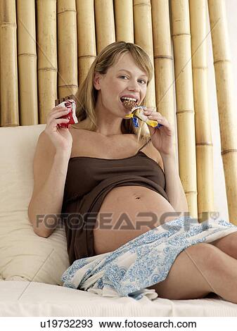 Stock Image - Pregnant woman eating sweets. Fotosearch