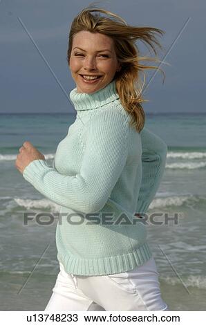 Stock Image - Running woman in turquoise pullover at the sea. Fotosearch