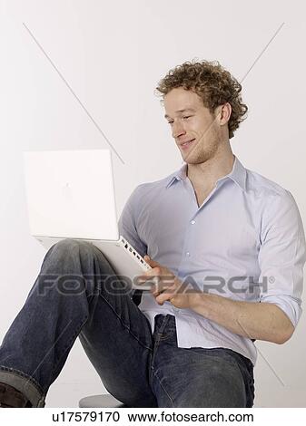 Stock Image - Smiling man using laptop. Fotosearch
