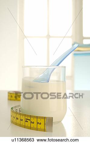 Stock Image - Tape measure and a glass with yoghurt. Fotosearch