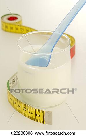 Stock Photo - Tape measure and a glass with yoghurt. Fotosearch