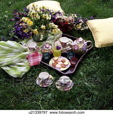 Stock Photo - Tea service and bunch of flowers in meadow. Fotosearch