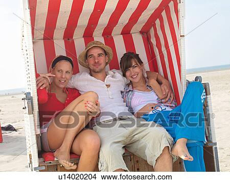 Picture - Three friends in a wicker beach chair. Fotosearch