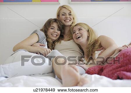 Stock Photo - three young women together on the bed. Fotosearch