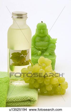 Picture - Traubenkernöl aus weißen Trauben, mit einem grünen Handtuch, weißen Weintrauben und einer grünen Buddha-Kerze. Fotosearch