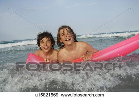 Stock Photo - Two boys at the seaside with air matress. Fotosearch