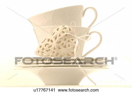 Stock Image - White cups decorated with a white heart. Fotosearch