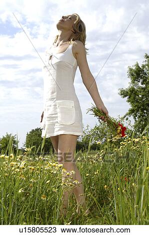White dressed woman is enjoying the sun in a meadow View Large Photo Image Stock Image - White dressed woman is enjoying the sun in a meadow. Fotosearch