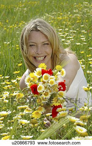 White dressed women is sitting with a bunch of flowers in a meadow View Large Photo Image Stock Image - White dressed women is sitting with a bunch of flowers in a meadow. Fotosearch