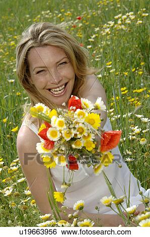 White dressed women is sitting with a bunch of flowers in a meadow View Large Photo Image Stock Photograph - White dressed women is sitting with a bunch of flowers in a meadow. Fotosearch