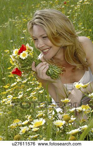 White dressed women is sitting with a bunch of flowers in a meadow View Large Photo Image Stock Photograph - White dressed women is sitting with a bunch of flowers in a meadow. Fotosearch