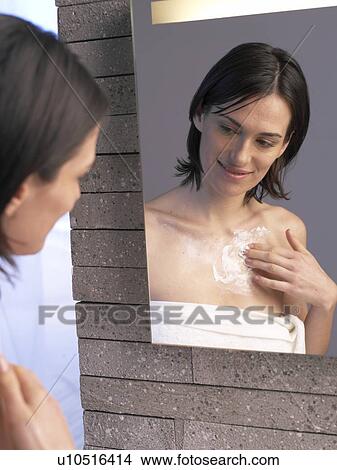 Picture - Woman applies lotion to her decollete. Fotosearch