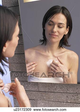 Woman applies lotion to her decollete View Large Photo Image Stock Photo - Woman applies lotion to her decollete. Fotosearch