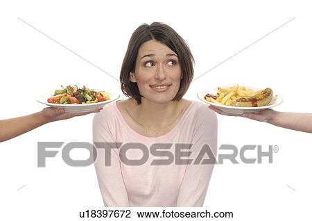 Stock Image - Woman deciding between health food and fast food. Fotosearch