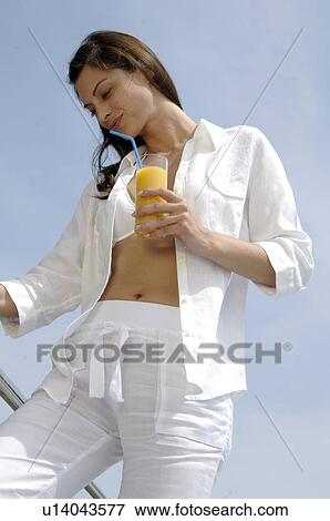 Stock Photo - Woman dressed in white enjoying a drink at the swimming pool. Fotosearch