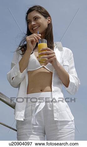 Stock Photo - Woman dressed in white is enjoying a drink. Fotosearch