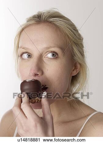 Stock Image - Woman eating chocolate marshmallow. Fotosearch