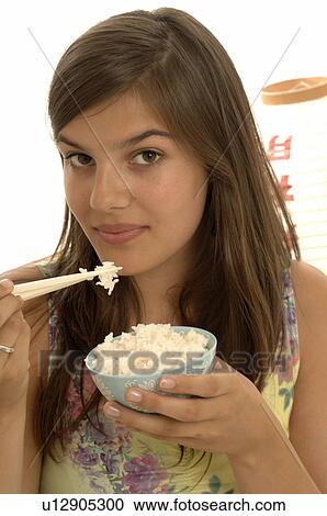 Stock Image - Woman eating rice with chopsticks. Fotosearch