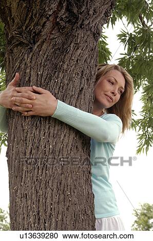 Woman embraces a tree in a meadow View Large Photo Image Stock Image - Woman embraces a tree in a meadow. Fotosearch
