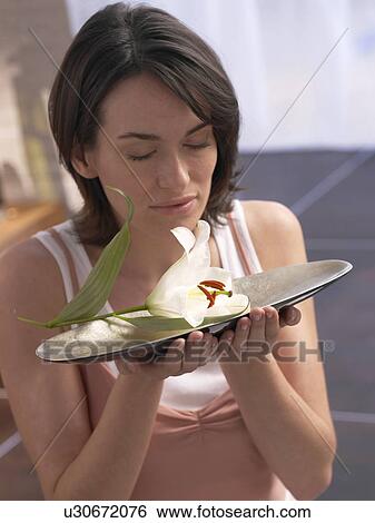 Stock Photograph - Woman holding tray wth a lily bolssom lying on it. Fotosearch