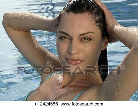 Stock Photograph - Woman in a swimming pool is running her hands over her hair. Fotosearch