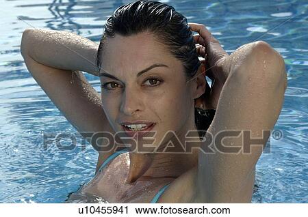 Stock Image - Woman in a swimming pool with hands going through her hair. Fotosearch