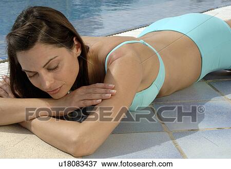 Stock Photo - Woman in a turquoise bikini is lying at the swimming pool. Fotosearch
