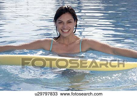 Stock Image - Woman in swimming pool with water aerobic device. Fotosearch