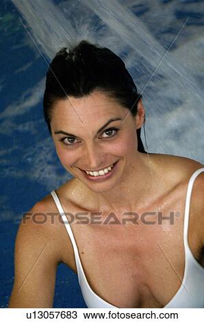 Stock Image - Woman in the swimming pool unter a shower. Fotosearch