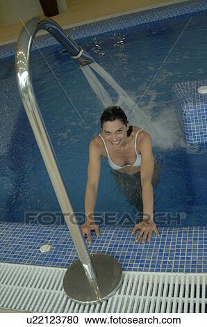 Stock Image - Woman in the swimming pool unter a shower. Fotosearch