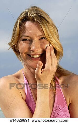 Stock Image - Woman is applying sunlotion. Fotosearch