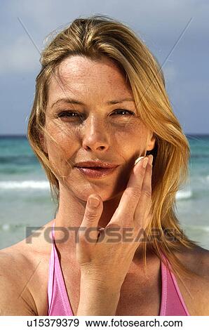 Stock Photo - Woman is applying sunlotion. Fotosearch