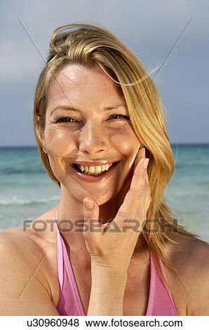 Stock Photo - Woman is applying sunlotion. Fotosearch