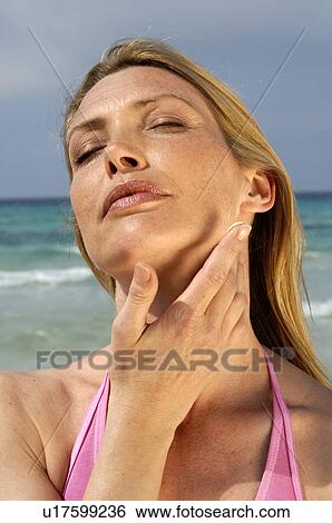 Stock Photograph - Woman is applying sunlotion. Fotosearch